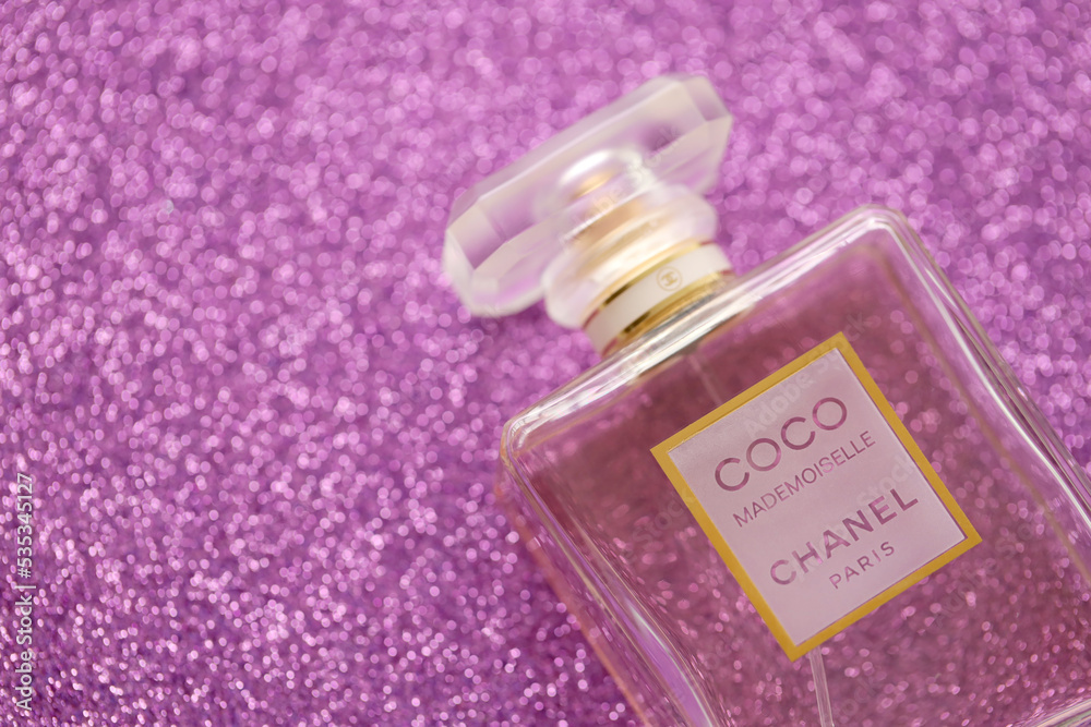 TERNOPIL, UKRAINE - SEPTEMBER 2, 2022 Coco Mademoiselle Chanel Paris  worldwide famous french perfume bottle on shiny glitter background in  purple colors Stock Photo