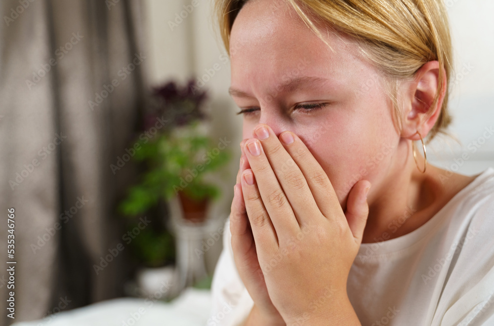 The sick girl coughs heavily, covering her mouth with her hands. The sick girl coughs heavily, covering her mouth with her hands.