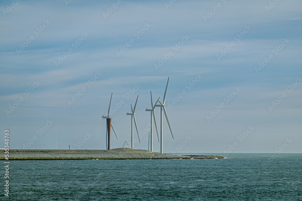 Rotterdam, Netherlands - July 11, 2022: Group of windmills at lands end into North Sea under blue sky, where entrance to port is.