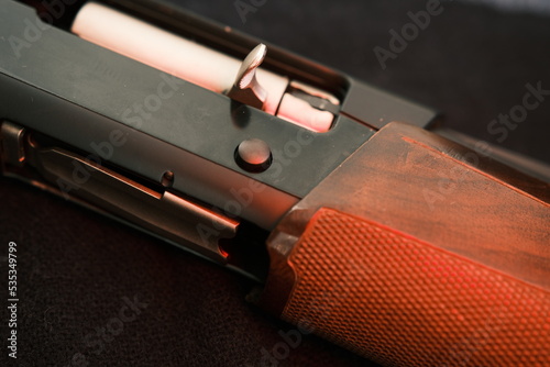 Closeup shotgun shutter. Hunting semi-automatic shotgun with wooden butt on dark background