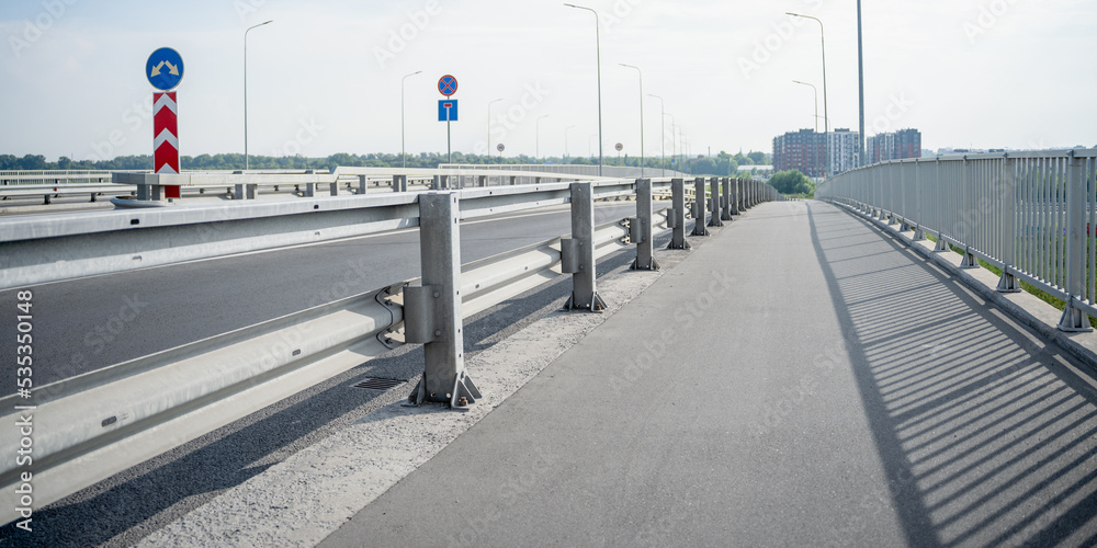 roadway of the bridge with metal railings high-rise buildings on the background