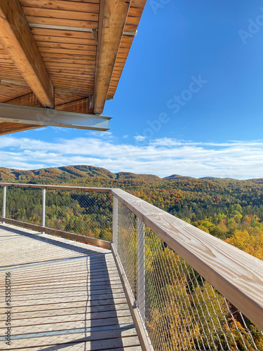 Bridge structure over the canopy. View of the mountains and colored trees at fall. High platform above the tree tops. Wooden tower structure. Autumn in the park.