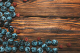 Ripe, blue grapes and raspberries lie on a wooden brown background.