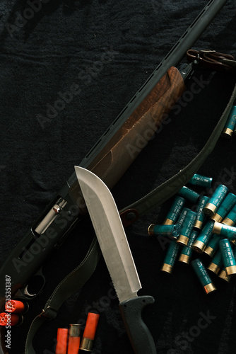 Weapon on black cloth: knife, rifle, shells,top view. Top view of knife, rifle, shells.