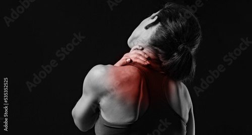 Strong sporty woman doing the hands the massage to relax the tension neck and blades in sport wear with red highlighted on empty copy space. Sports exercising injury. Closeup. Concept of medicine