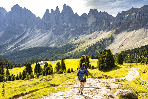 Athletic woman walks along beautiful hike trail at Seceda in the dolomites at noon. Seceda, Saint Ulrich, Dolomites, Belluno, Italy, Europe.