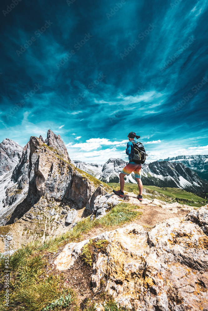 Athletic man stands at beautiful view point and enjoys view on Seceda in the dolomites in the afternoon. Seceda, Saint Ulrich, Dolomites, Belluno, Italy, Europe.