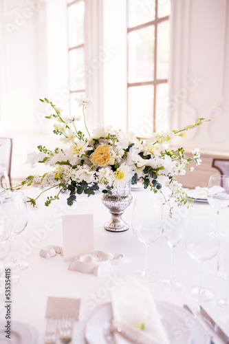 Festive table decorated with white flowers for seating guests at a wedding banquet. Vertical banner, selective focus