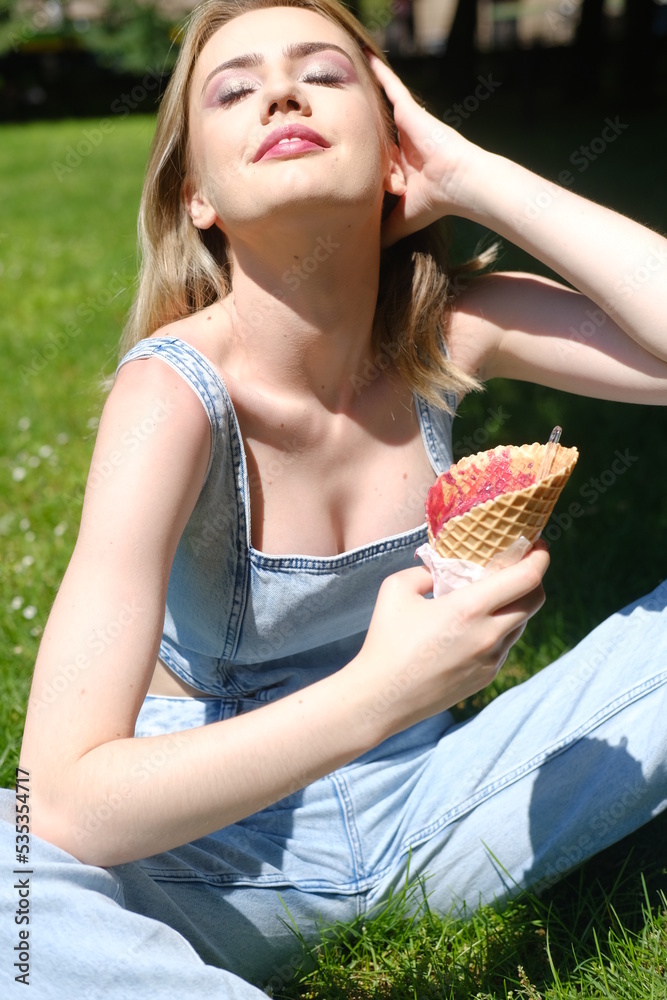 Girl in the blue jeans denim eating red ice cream
