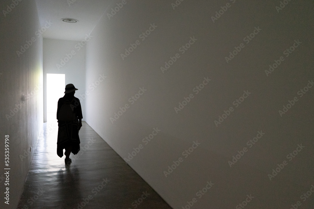 Donna in controluce che cammina in una galleria