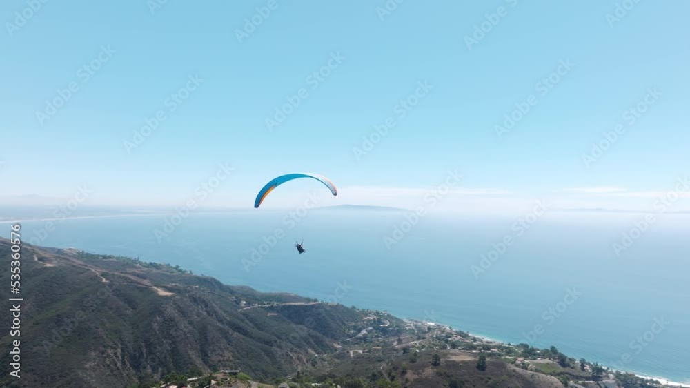 Extreme paraglider flying above Los Angeles in Malibu mountains. Freedom concept. Adventure sports video paragliders flying over mountains on beautiful sunny day. Popular paragliding region in America Extreme paraglider flying above Los Angeles in Malibu mountains. Freedom concept. Adventure sports video paragliders flying over mountains on beautiful sunny day. Popular paragliding region in America