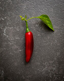 Red jalapeno with leaf on a granite surface