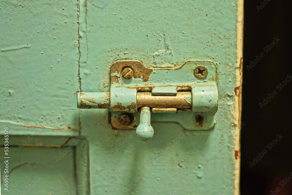 one old gray green metal latch on a wooden plank door one old gray green metal latch on a wooden plank door