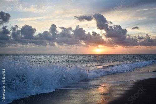 Beautiful sunset scene on a beach with sea, waves and clouds