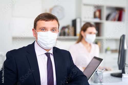 Portrait of adult businessman in surgical medical mask looking at camera. Concept of business people and health care in coronavirus pandemic..