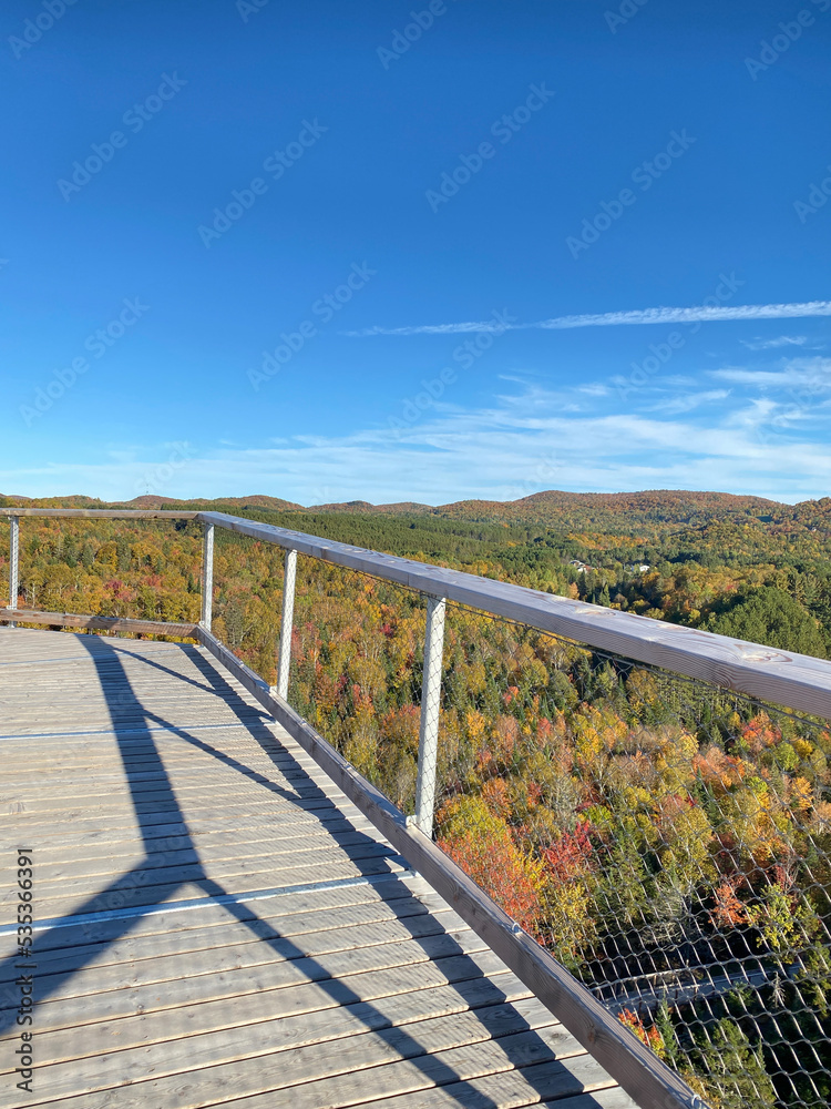Bridge over the forest and mountains. Wooden walkways above the tree tops. Footpath in the wood. Autumn in the park. High platform on a beautiful day in early fall with colored trees. Hiking trail.