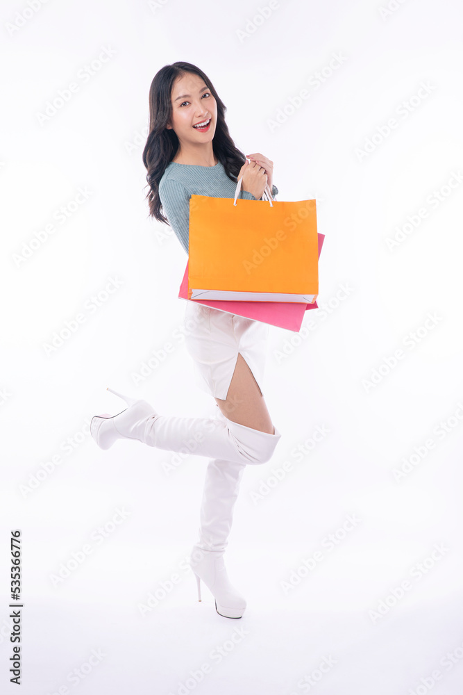 Enjoyment excited asian woman carry shopping bags standing full body on white background. Trendy happy shopper consumer young girl holding shopping paper bags with copy space over isolated background. Enjoyment excited asian woman carry shopping bags standing full body on white background. Trendy happy shopper consumer young girl holding shopping paper bags with copy space over isolated background.