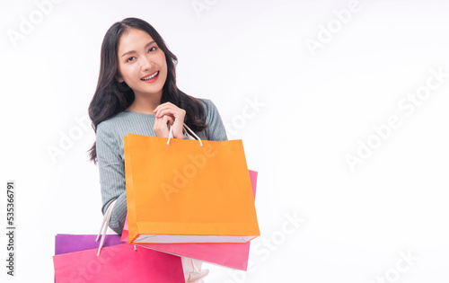 Enjoyment excited asian woman carry shopping bags standing on white background. Trendy happy shopper consumer carefree young girl holding shopping paper bags with copy space over isolated background. photo