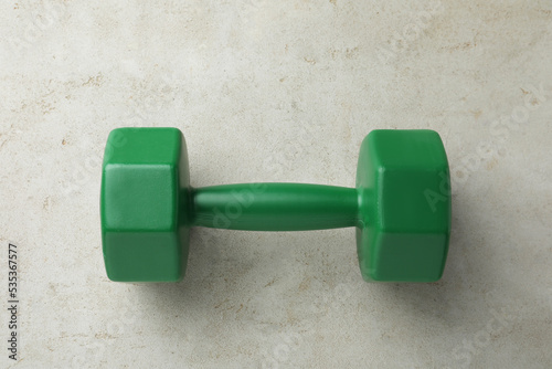 One green dumbbell on light grey table, top view