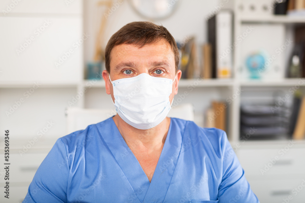 Close up portrait of male doctor wearing disposable face mask in medical office