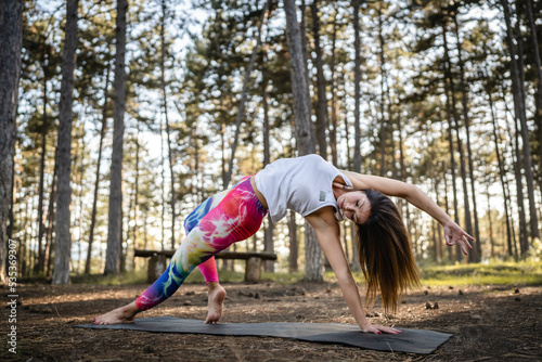 One caucasian woman practice yoga in the nature in woods or park alone healthy lifestyle meditation and modern relaxation antistress stretching concept copy space front view