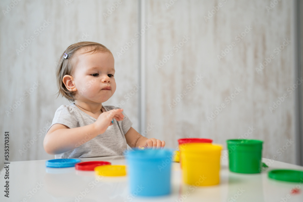 One girl small caucasian toddler child playing with colorful plasticine on the table at home alone childhood and growing up development concept copy space One girl small caucasian toddler child playing with colorful plasticine on the table at home alone childhood and growing up development concept copy space