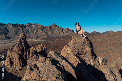Girl sitting on the rocks in Teide National Park. Volcanic landscape. Roques de García trail. Tenerife, Canary islands, Spain.