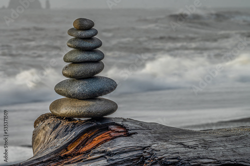 Cairn on a log on the beach at the ocean