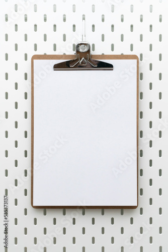 Clipboard with blank paper and copyspace for text on peg board