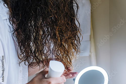 Woman spraying her hair with water to to form curls photo