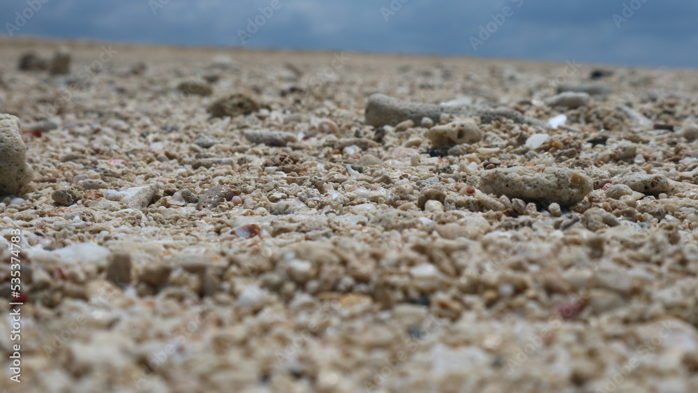Sand and rocks by the beach against a backdrop of blue sky and soft white clouds. great for backgrounds and wallpapers Sand and rocks by the beach against a backdrop of blue sky and soft white clouds. great for backgrounds and wallpapers