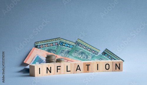 Letters of the alphabet Inflation on wood cubes with currency notes and coins at the background. Inflation concept.