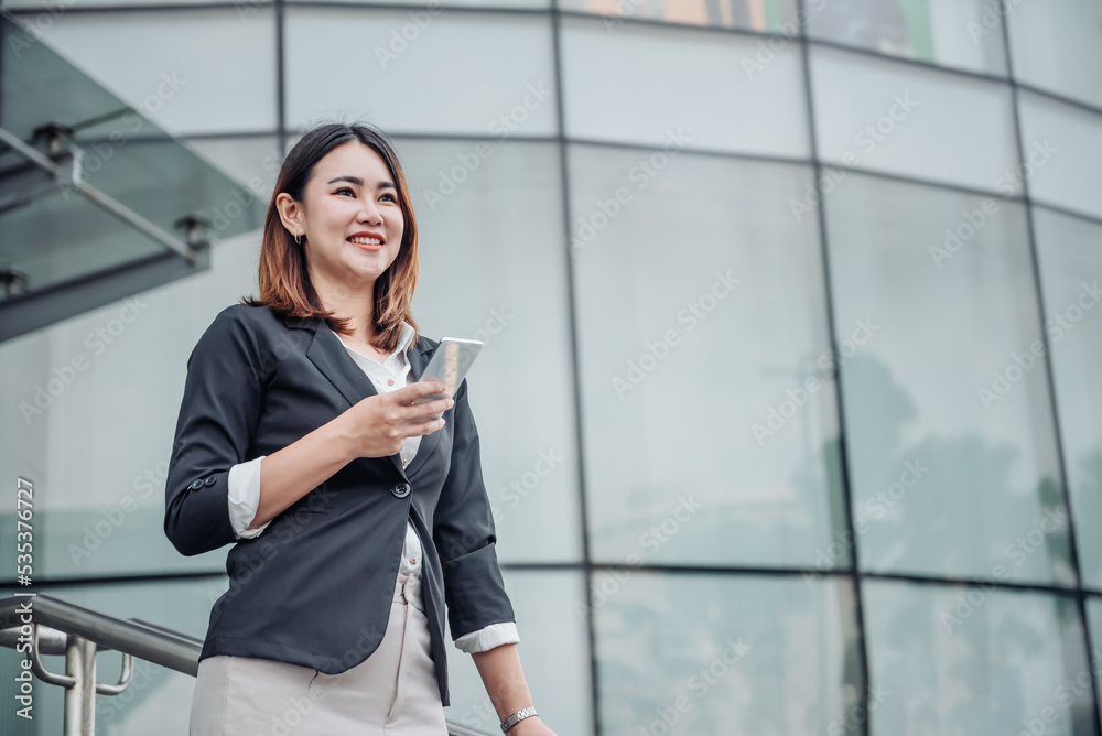 Young Asian businesswoman talking on phone and walking in airport before business trip. Beautiful woman passenger has mobile call and discusses something with smile, holds coffee in hand Young Asian businesswoman talking on phone and walking in airport before business trip. Beautiful woman passenger has mobile call and discusses something with smile, holds coffee in hand