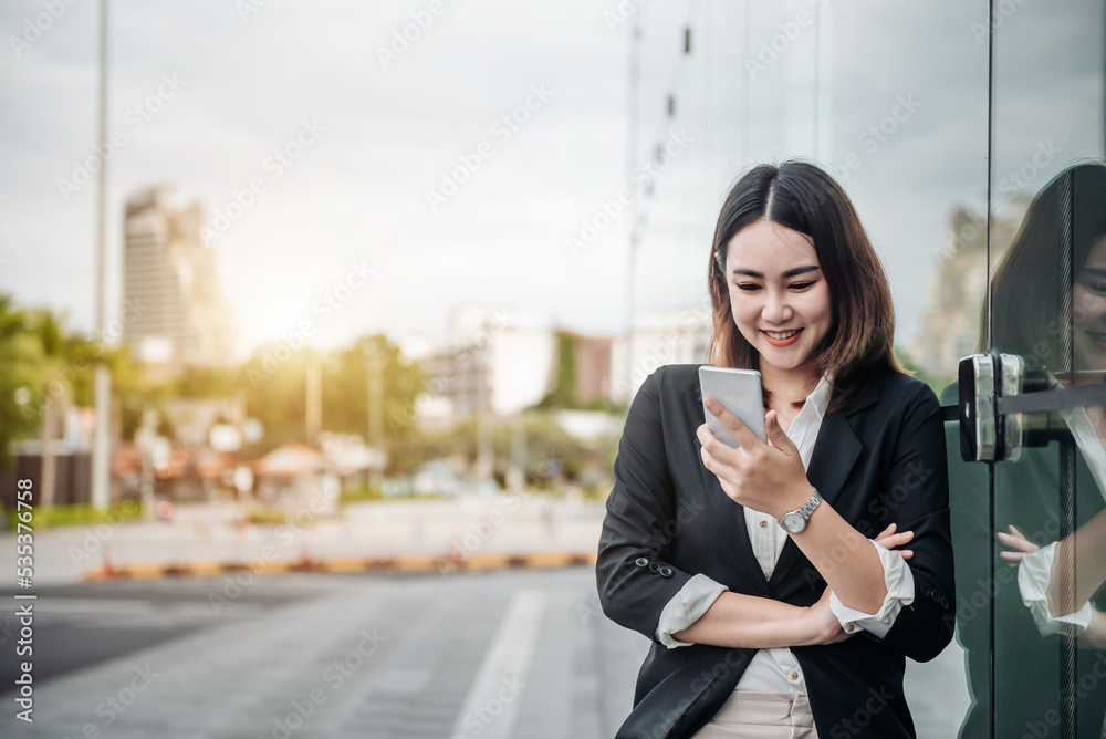 Young Asian businesswoman talking on phone and walking in airport before business trip. Beautiful woman passenger has mobile call and discusses something with smile, holds coffee in hand