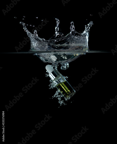 Glass bottle of anti aging serum splashing into water on black background,Cosmetic for skin care