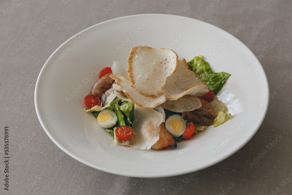 Caesar salad with roasted chicken breast, croutons, cherry tomatoes and parmesan on white plate Caesar salad with roasted chicken breast, croutons, cherry tomatoes and parmesan on white plate