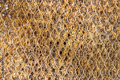 Selective focus macro of a dirty kitchen range hood filter clogged with grease.