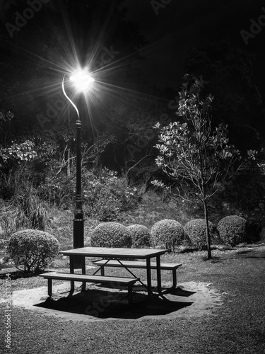 Night scenery of bench, picnic table and street light in park