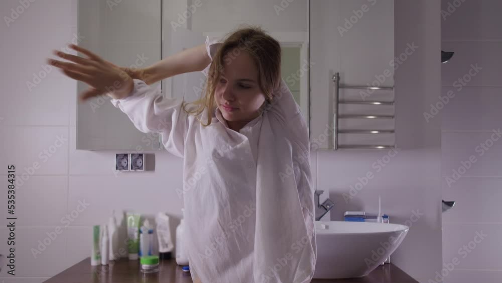 A young sleepy woman stretches and begins to dance slowly in the morning in the bathroom A young sleepy woman stretches and begins to dance slowly in the morning in the bathroom