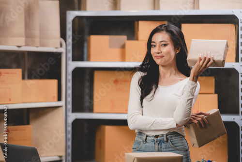 Asian woman e-business entrepreneur checking order and packing parcel box of product shipping delivery business, freelance marketing owner having online cyberspace to work with logistic package job