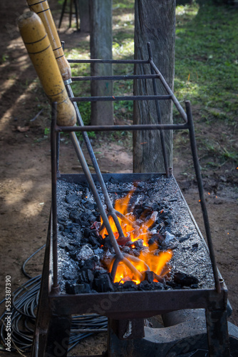 a cattle-marking iron being heated over the coals