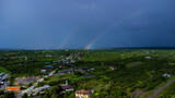 Rainbow in the sky after heavy rain in the countryside. Top view of a river overflowing after heavy rain and flooding of agricultural fields in rural. Climate change concept.