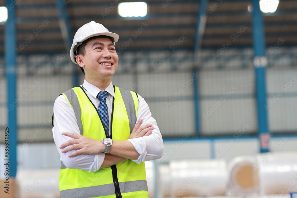 Asian engineering worker man portrait standing and arm crossed with happy smiling face with confident and blurred large warehouse background Asian engineering worker man portrait standing and arm crossed with happy smiling face with confident and blurred large warehouse background