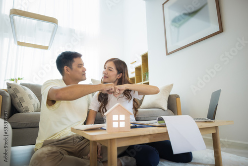 Asian couple in home or house. To bump punch, compare prices, interest, credit and calculate together. Include laptop, calculator and document on table. Concept for marriage, family, loan, finance.
