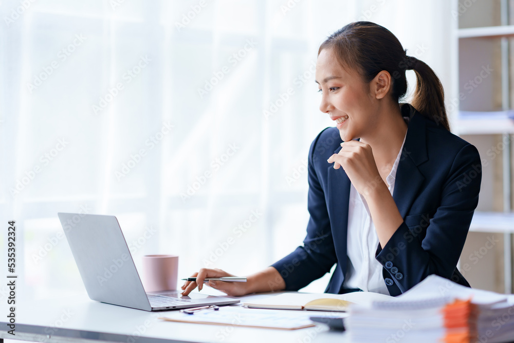 Portrait of smiling Asian businesswoman enjoying work ideas sitting on a laptop at the office. Portrait of smiling Asian businesswoman enjoying work ideas sitting on a laptop at the office.