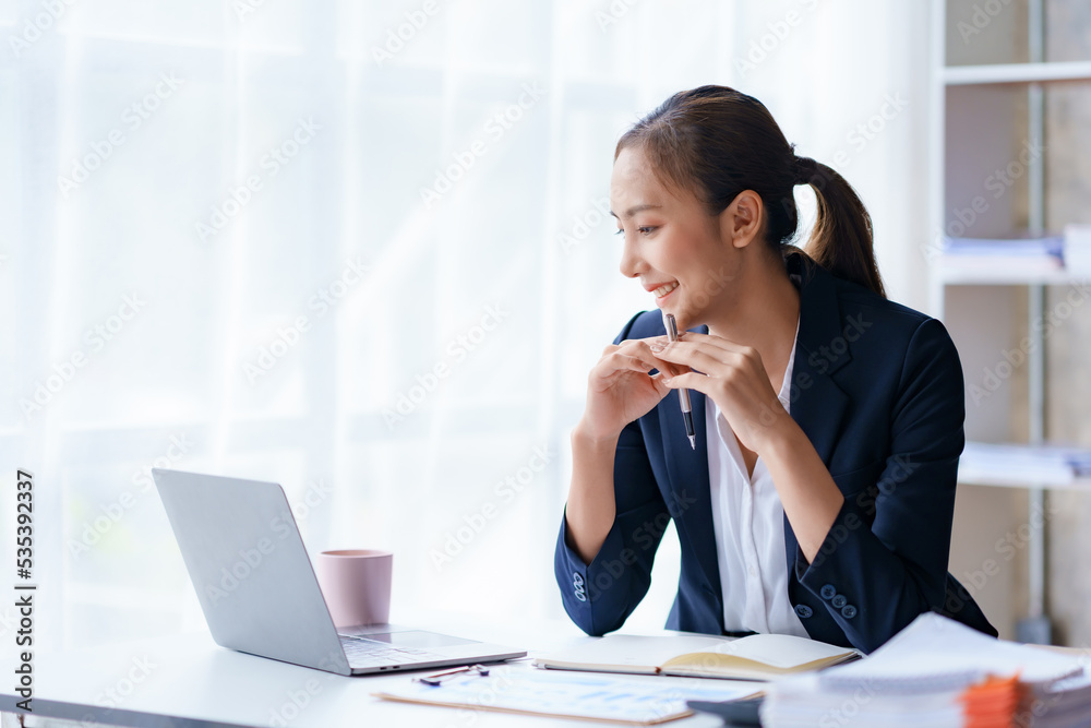Portrait of smiling Asian businesswoman enjoying work ideas sitting on a laptop at the office. Portrait of smiling Asian businesswoman enjoying work ideas sitting on a laptop at the office.