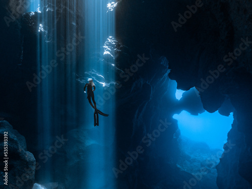 Person diving inside cave under water photo