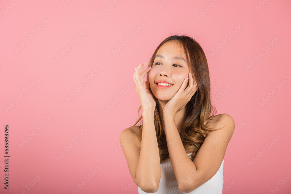 Femininity. Asian beautiful young woman smiling mask cosmetic patches gel under the eyes, Portrait female touching clean skin medical hydrogel eye patch on face, isolated on pink background, skincare Femininity. Asian beautiful young woman smiling mask cosmetic patches gel under the eyes, Portrait female touching clean skin medical hydrogel eye patch on face, isolated on pink background, skincare