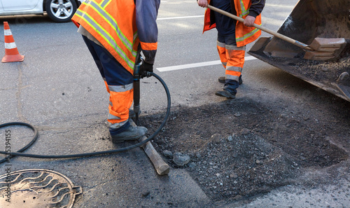 The workers' brigade clears a part of the asphalt with shovels in road construction photo