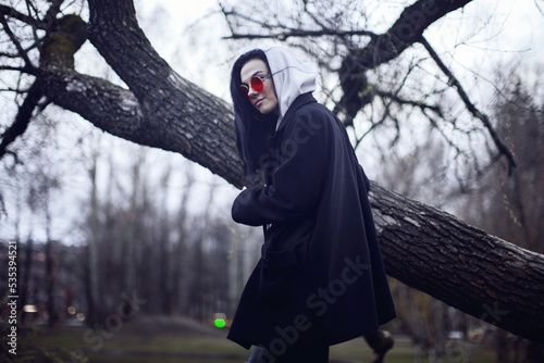 Woman in black coat standing near brown tree photo